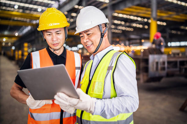 two asian engineers using a laptop in a factory.